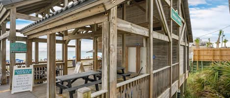 A wooden beachside structure with a covered seating area and a sign for Emerald Shores.