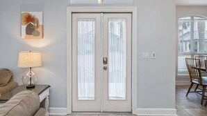 Une porte blanche avec des panneaux de verre dépoli, une lampe fixée au mur et un coin repas avec des chaises et une table.