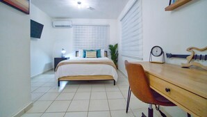 Une chambre à coucher avec un lit, un bureau, une chaise, une horloge et une guitare.