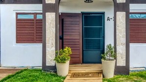 A modern house with a dark brown door, stone pillars, and a wooden front step.