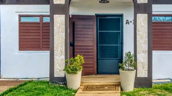 A modern house with a dark brown door, stone pillars, and a wooden front step.
