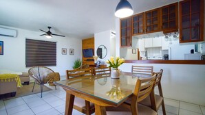 A modern kitchen with wooden cabinets, a dining table with chairs, and a ceiling fan.