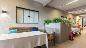 Een eethoek met een tafel, stoelen, een bank, een wandlamp en een brandblusser.