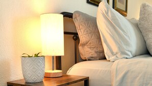 A neatly arranged bedroom with a bedside table, a lamp, and a bed with pillows. - Cozy Blue Cottage

 (Willcox)