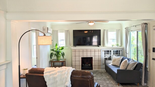 A living room with a fireplace, a television, a sofa, and a chair. - Cozy Blue Cottage

 (Willcox)
