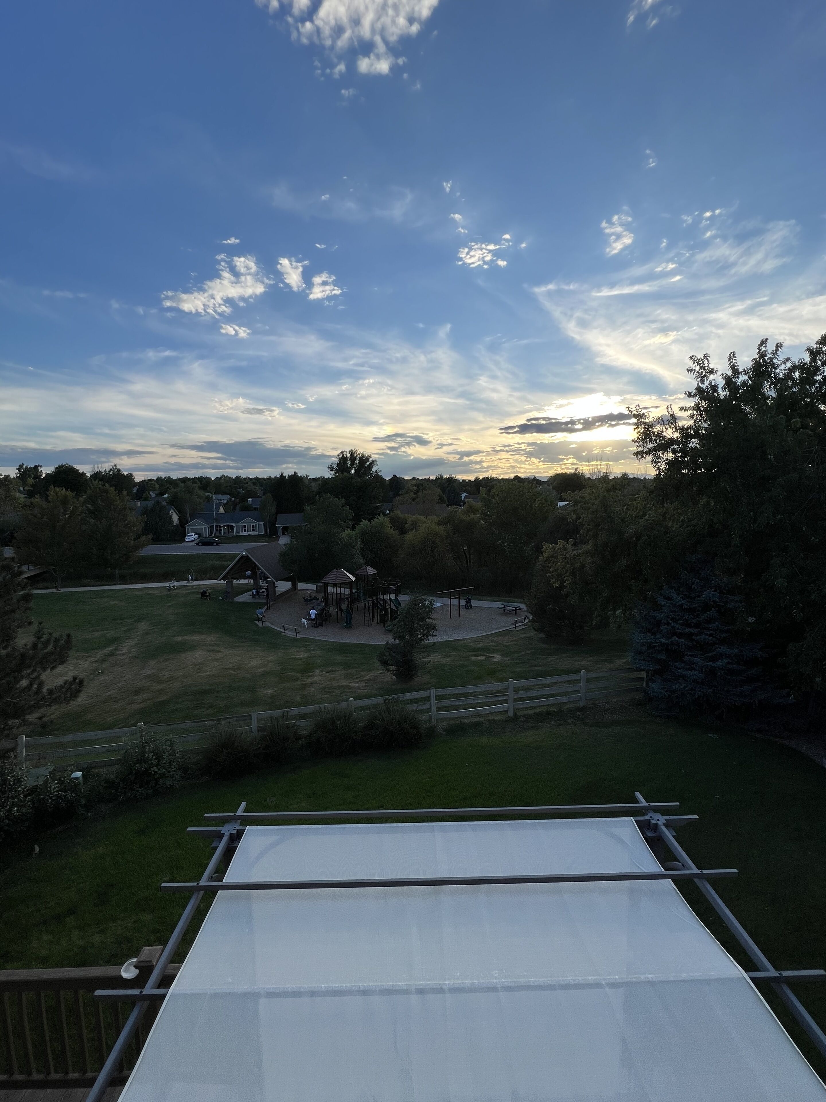 Vista de un parque con un pabellón, mesas de picnic y un parque infantil.