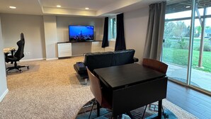 Uma sala de estar moderna com uma televisão grande, uma mesa de jantar e um sofá.