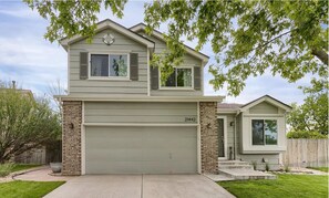 A two-story house with a garage, a brick column, and a number '21442' on the garage door. - Green Jay House (Centennial)