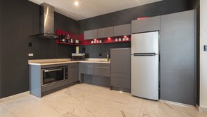 A modern kitchen with a built-in oven, microwave, stainless steel range hood, and a refrigerator. - Modern apartment in the center near the beaches (Playa del Carmen)
