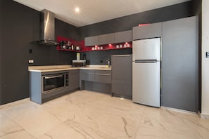 Una cocina moderna con horno integrado, microondas, campana extractora de acero inoxidable y refrigerador.