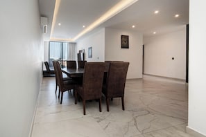 Un comedor moderno con suelo de mármol, una mesa redonda y seis sillas.