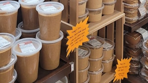 A display of various food items, including containers of what appears to be a creamy dessert and other baked goods, in a commercial setting.