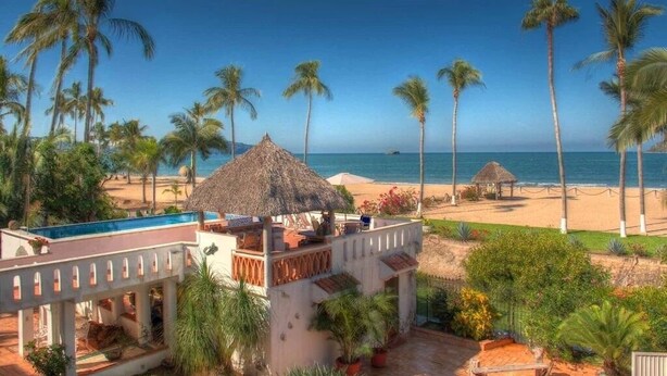 Un resort con piscina, playa y palmeras.