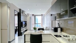 A modern kitchen with a central island, built-in appliances, and a large window providing natural light.