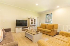 Una sala de estar con televisión, sofá, mesa de centro y ventana con vistas.