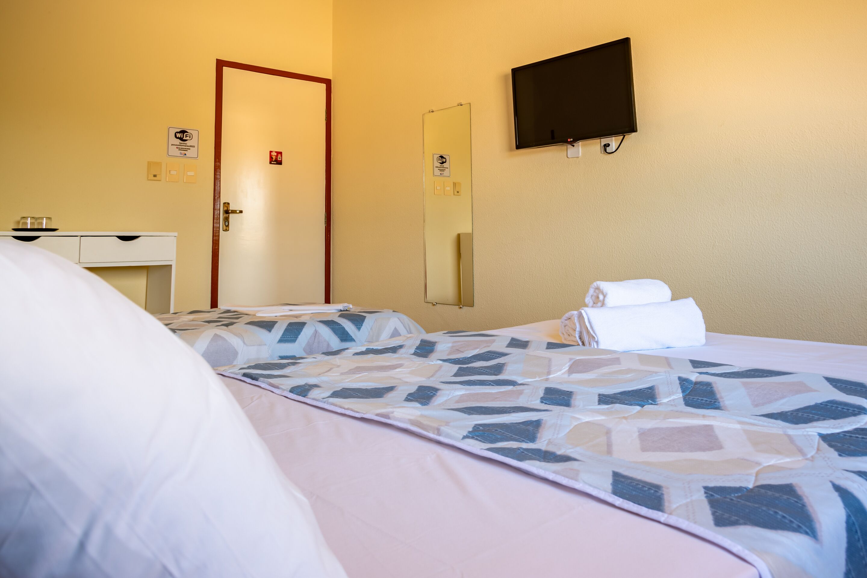 Una habitación de hotel con una cama, un escritorio, un espejo y un televisor.