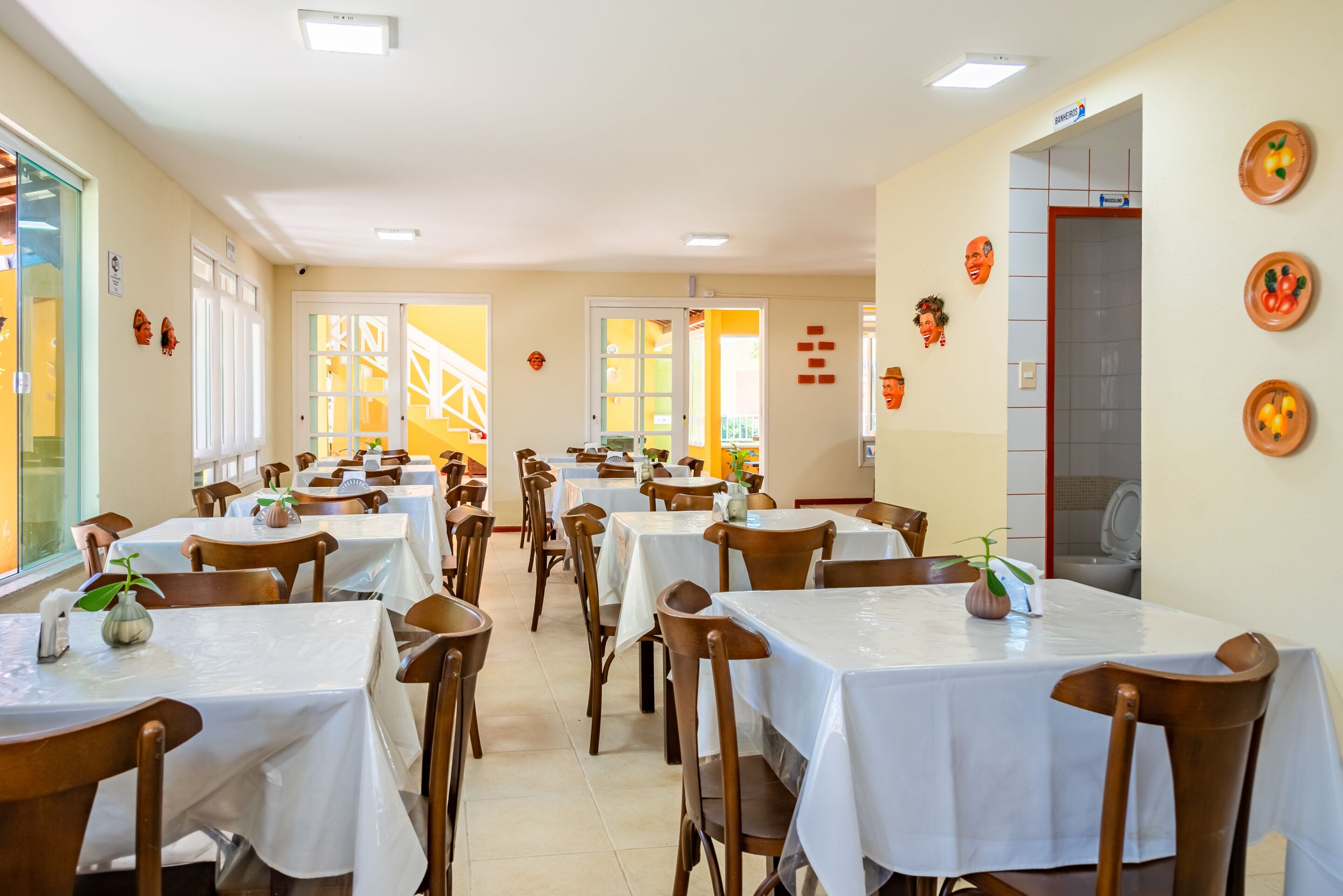 Ein Restaurant mit mehreren Tischen und Stühlen, einem Fliesenboden und einer Tür zu einem weiteren Raum.
