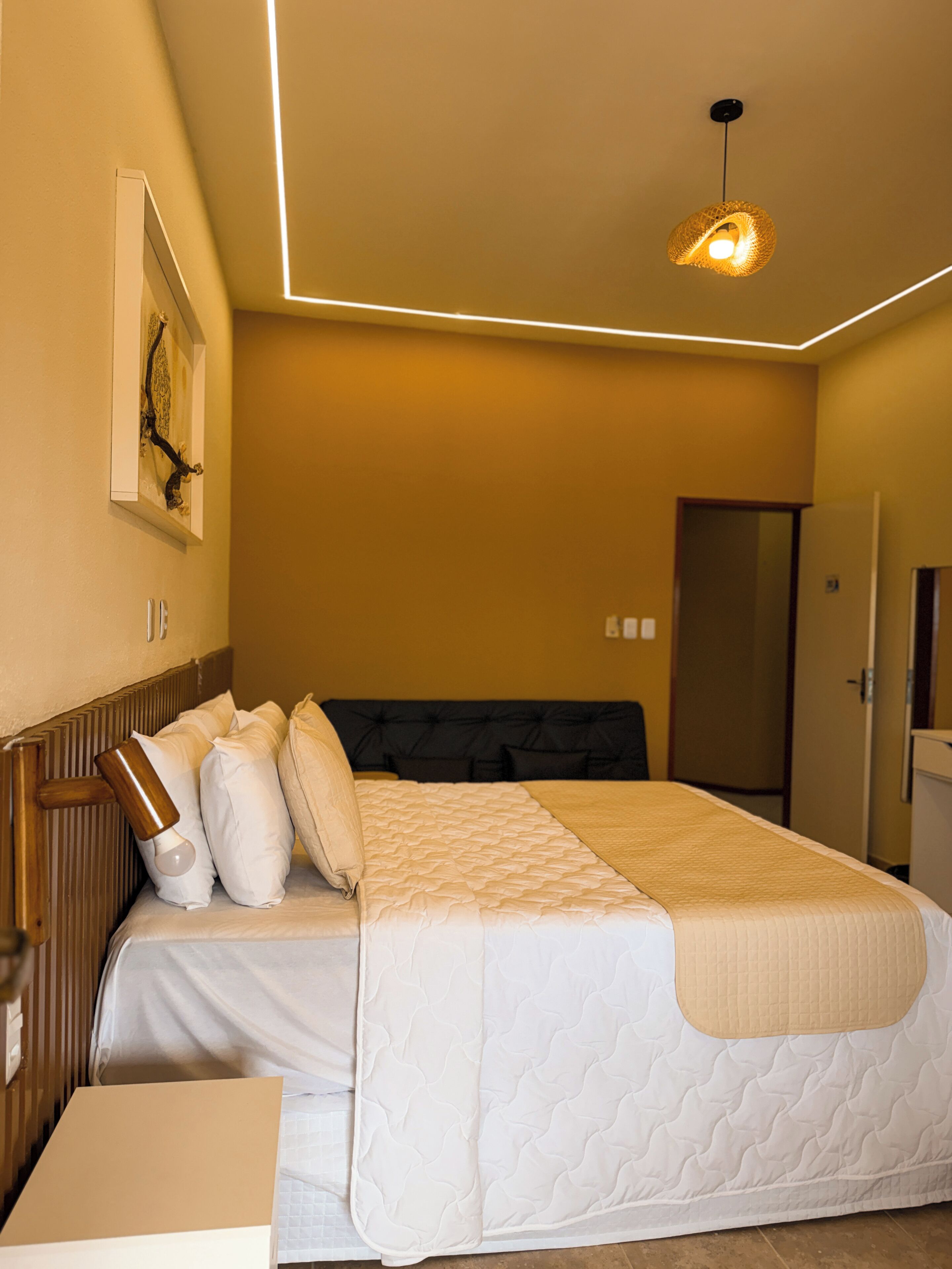 A bedroom with a bed, bedside table, and a hanging light fixture.
