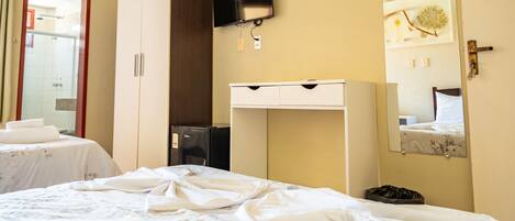 A hotel room with a bed, a wardrobe, a desk, a television, and a mirror.