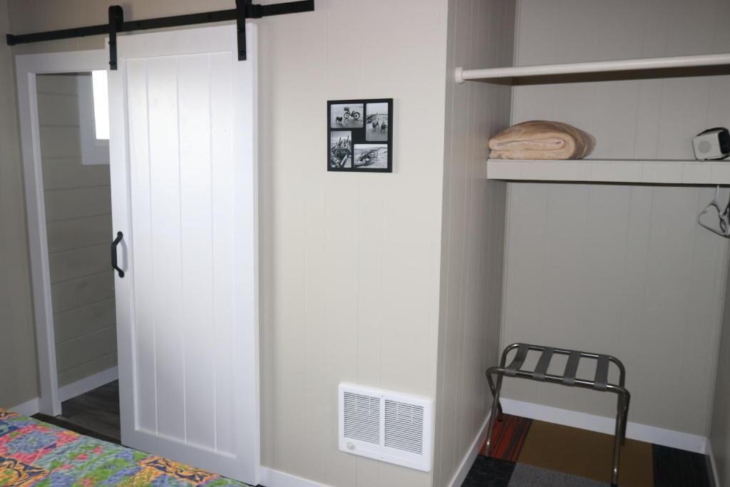 A bedroom with a bed, a wardrobe, a radiator, and a shelf with towels.