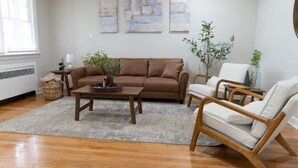 A living room with a brown sofa, a wooden coffee table, and two wicker chairs.