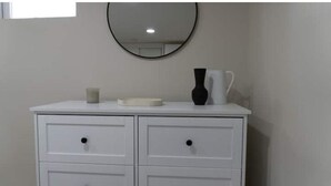 A white dresser with two drawers and a mirror above it.