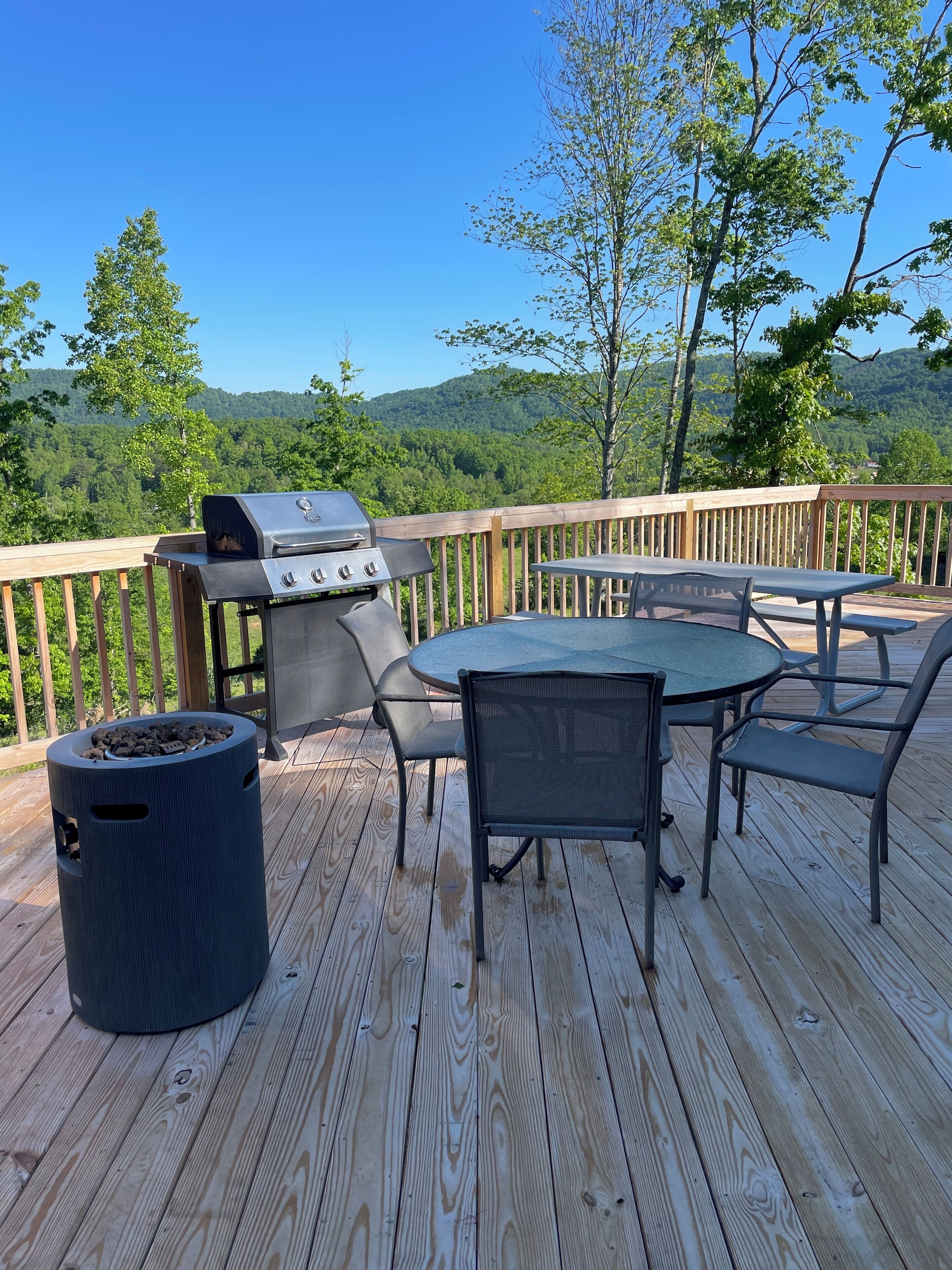 Un terrazzo in legno con una griglia barbecue e posti a sedere all'aperto.