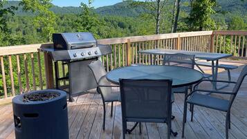 Un terrazzo in legno con una griglia barbecue e posti a sedere all'aperto.