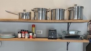 A kitchen with a stove, pots, and spices on shelves.