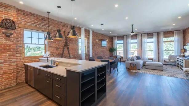 A spacious kitchen with a large island, dark cabinetry, and pendant lighting. - Historic Main Street Lofts - 3rd floor (Gunnison)