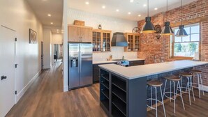 A modern kitchen with a central island, bar stools, and pendant lighting. - Historic Main Street Lofts - 3rd floor (Gunnison)