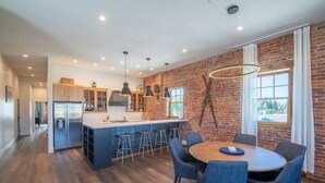 A modern kitchen with a central island, bar stools, and pendant lighting. - Historic Main Street Lofts - 3rd floor (Gunnison)
