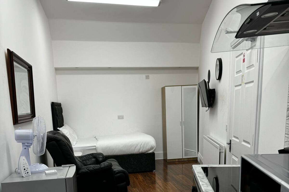 A compact hotel room with a bed, a small kitchenette, a seating area with a sofa, and a dining table.