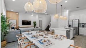 Una cocina moderna con armarios blancos, una isla central con pileta y electrodomésticos de acero inoxidable.