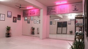 Ein Yoga-Studio mit rosafarbenen Wänden, gerahmten Motivationssprüchen und einer Spiegelwand, die den Raum reflektiert.