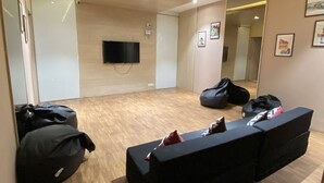Ein Zimmer mit einer schwarzen Couch, einem flachbildfernseher an der Wand und einem Holzboden.