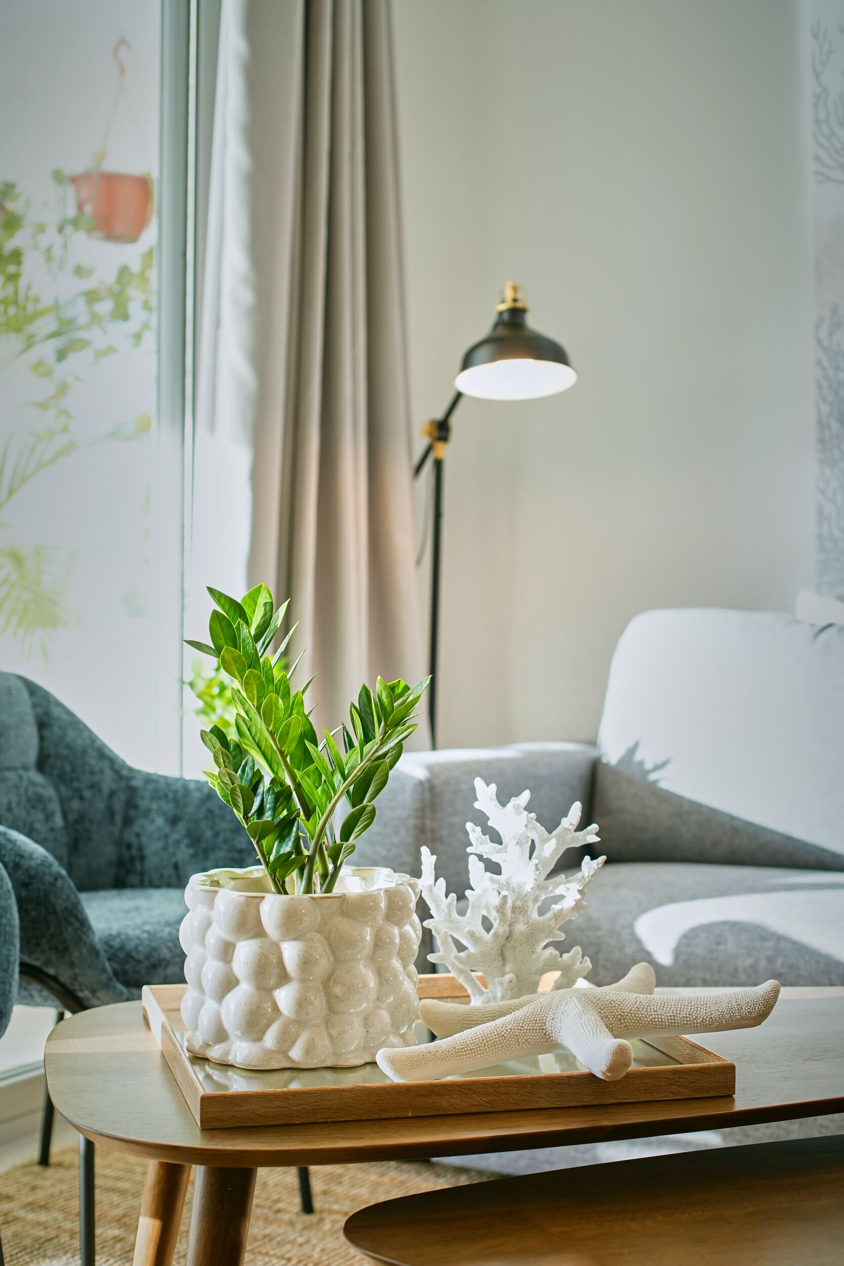 Ein modernes Wohnzimmer mit grauem Sofa, einem Holztisch und einer dekorativen Pflanzengruppe.