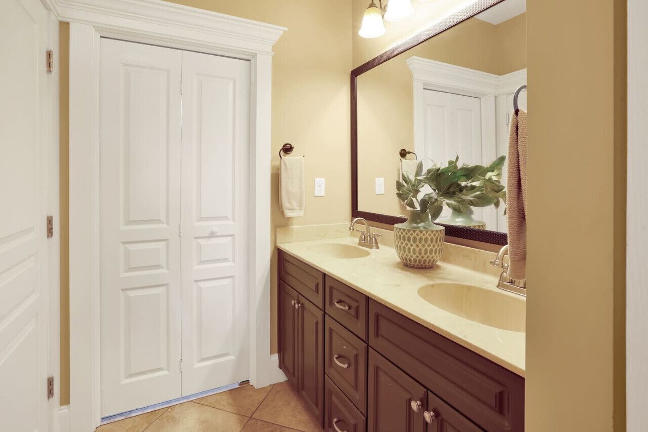 A bathroom with two sinks, a large mirror, and a potted plant.