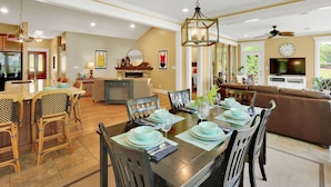 A spacious dining area with a high table set for six, surrounded by wicker chairs. A chandelier hangs above, and a television is mounted on the wall. - Lake front home, private dock, pet friendly (Appling)
