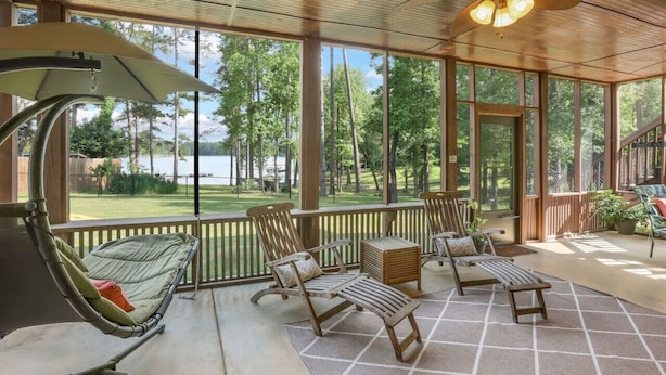 A covered outdoor area with a view of a lake, wooden furniture, and a ceiling fan. - Lake front home, private dock, pet friendly (Appling)