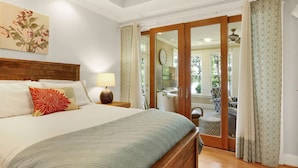 A bedroom with a wooden bed, a nightstand with a lamp, a large window, and a sliding glass door leading to a balcony. - Lake front home, private dock, pet friendly (Appling)