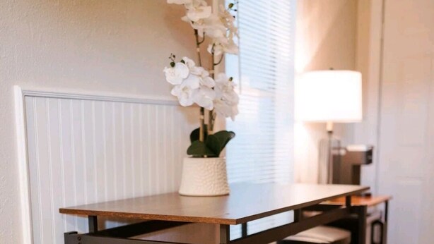 A kitchen with a wooden table and four stools. - Boutique Beeville Cottage (Beeville)
