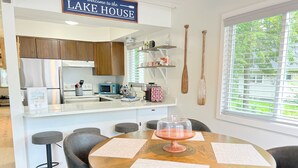 A modern kitchen with wooden cabinets, a central island, and a dining area with a round table and chairs.