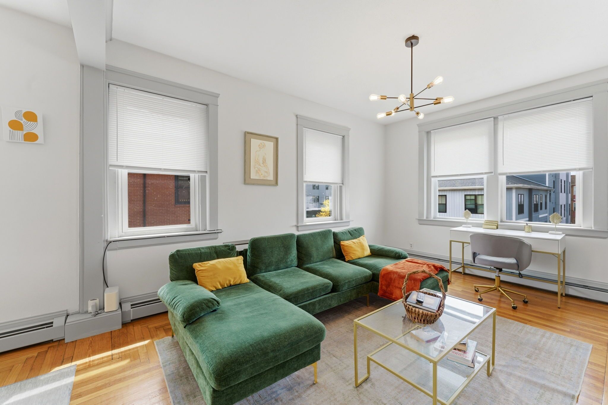 A modern living room with a sectional sofa, a desk, and a large window.