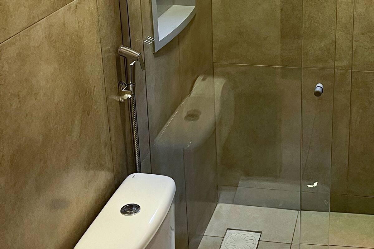 Un baño con ducha de vidrio, inodoro y dispensador de toallas de papel.