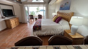 A hotel room with a bed, a TV, a desk, and a view of the outdoors. - Oceanfront studio apartment  (Rincón de Guayabitos)