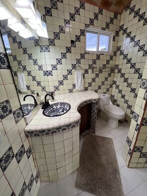 Un baño con baldosas estampadas, un lavabo, un inodoro y una ventana.