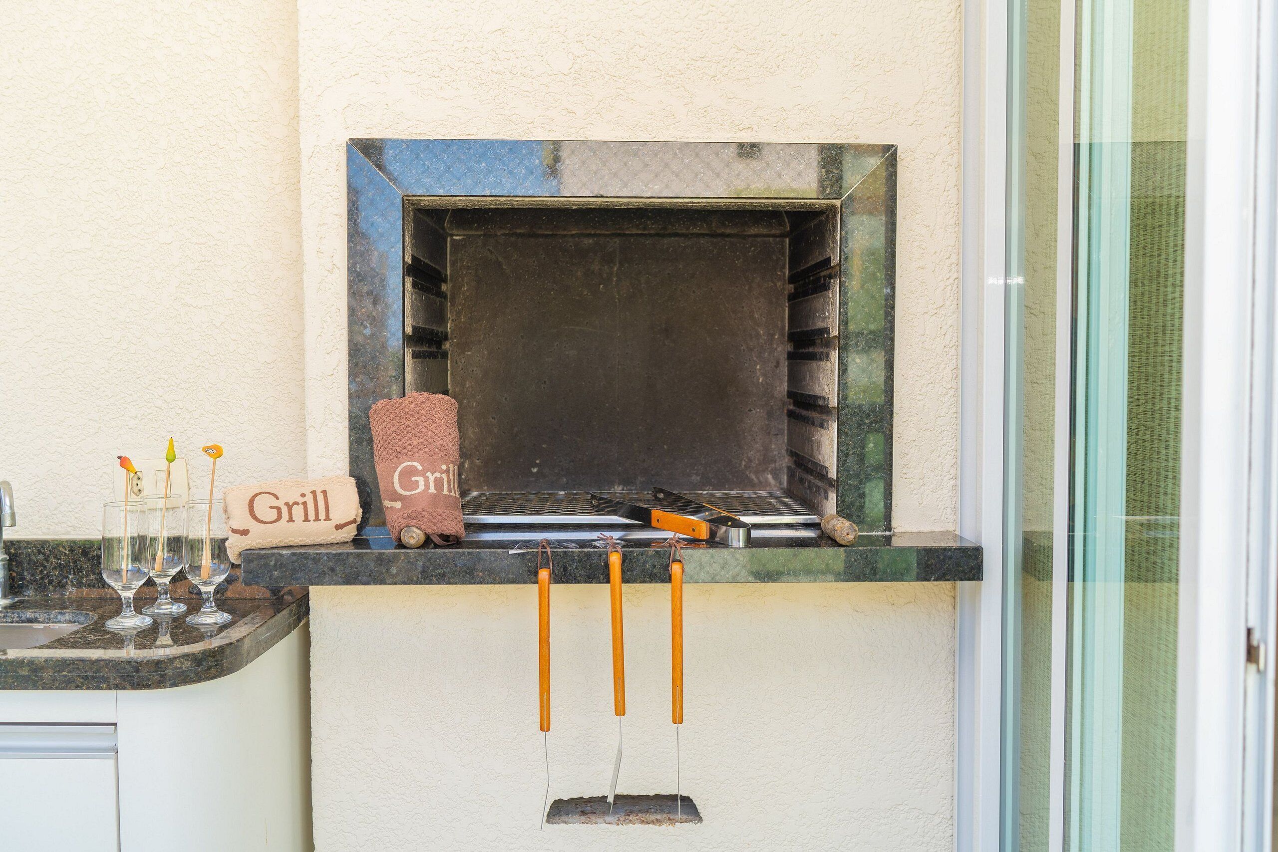 A kitchen with a grill, a towel labeled "Grill", and three glasses with skewers.