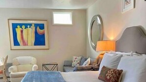 Ein Hotelzimmer mit einem großen Bett, einem Sessel, einem kleinen Tisch, einem Bild an der Wand und einem Fenster.