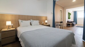 A hotel room with a bed, two bedside tables with lamps, a desk, and a chair. - Livramento Residence (Ponta Delgada)